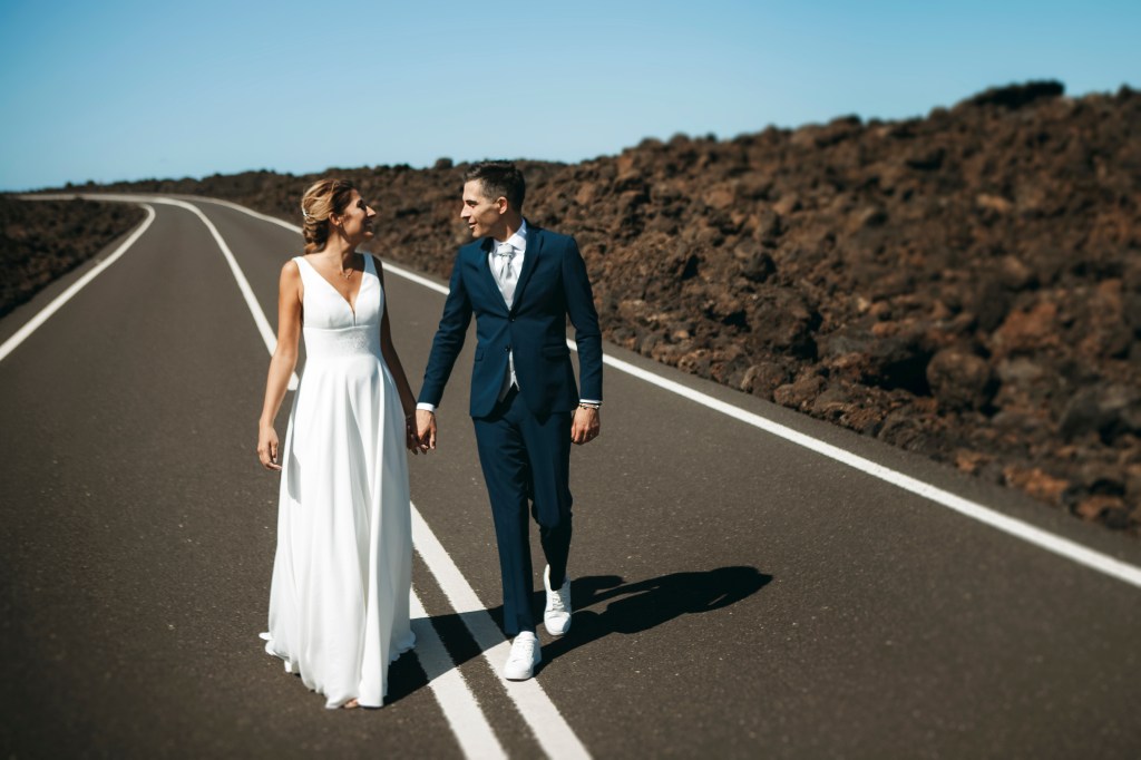 Couple walking hand-in-hand on a volcanic road in Lanzarote, capturing their elopement adventure.