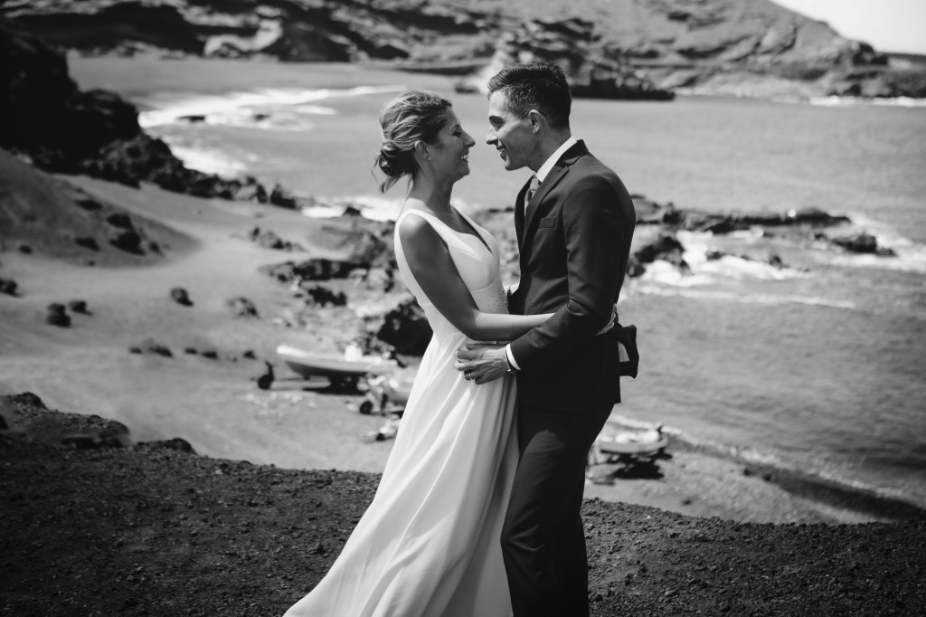 Stunning bride and groom on a cliff overlooking El Golfo Beach, showcasing romantic Lanzarote elopement photography