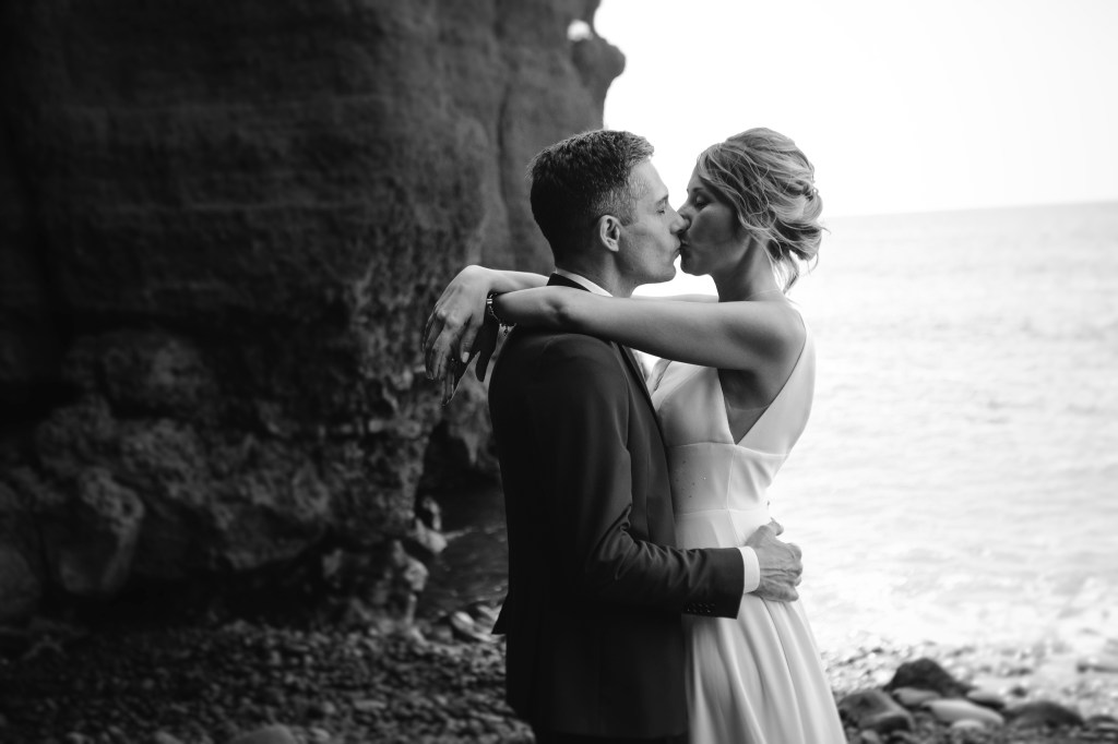 Black and white photo of a bride and groom kissing on El Golfo beach, captured by a wedding photographer in Lanzarote