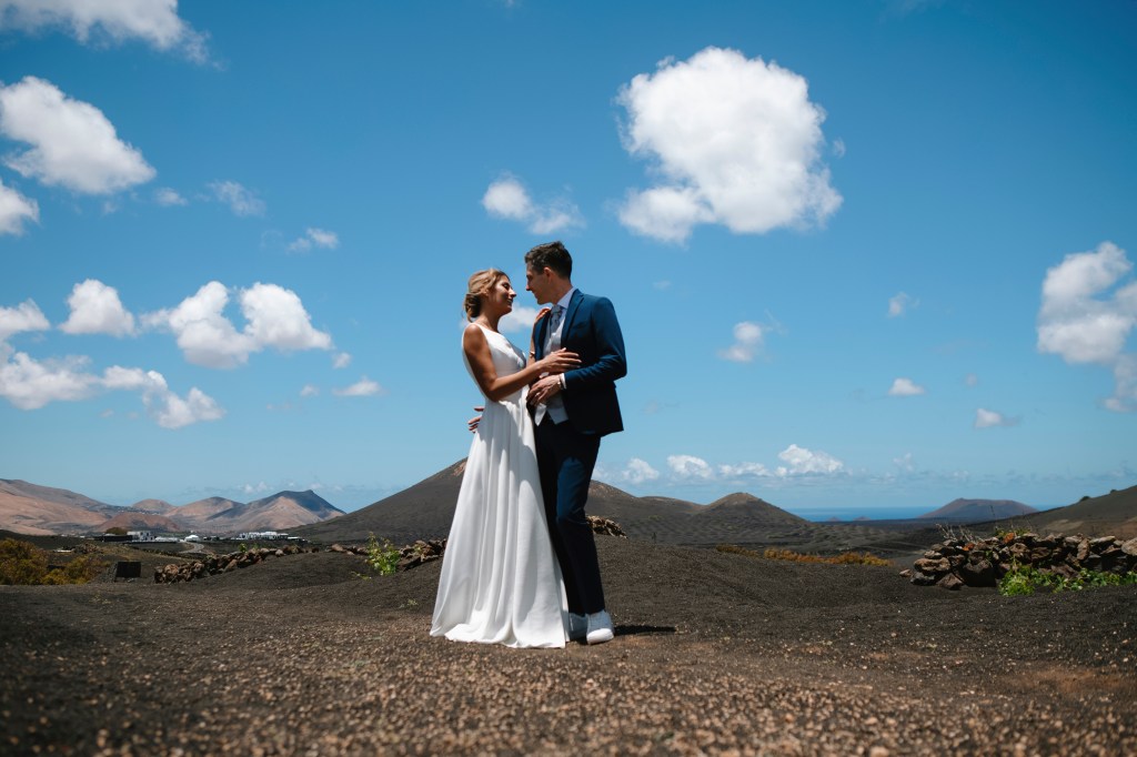 Wedding photographer in Lanzarote captures a romantic moment of a bride and groom embracing in La Geria's stunning volcanic landscape
