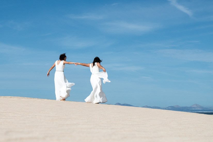 Two brides sharing a sunset kiss - emotional same-sex wedding portraits in Fuerteventura's desert landscape
