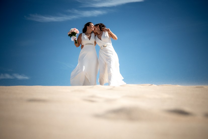 LGBTQ+ wedding celebration - brides dancing barefoot in Corralejo's sand, photographed by Fuerteventura's queer-friendly pro
