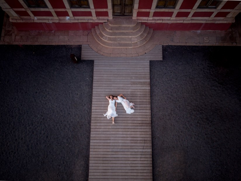 Drone view: Lesbian couple kisses on El Cotillo lighthouse - award-winning LGBT wedding photography in Fuerteventura