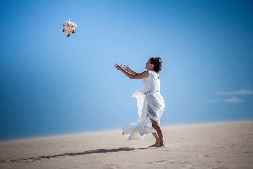 Genuine lesbian love - tender embrace between brides in Fuerteventura's dramatic dune scenery