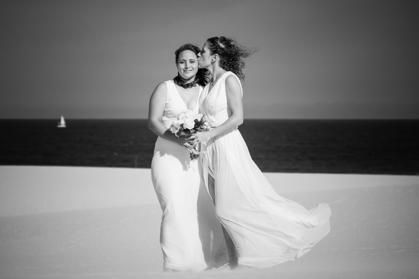 Modern queer love story - stylish brides posing against Corralejo's wind-sculpted sands