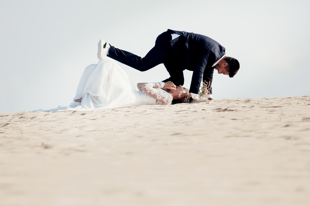Bride and groom felt down to the sand, they all are laughing during the wedding photoshoot in Lanzarote