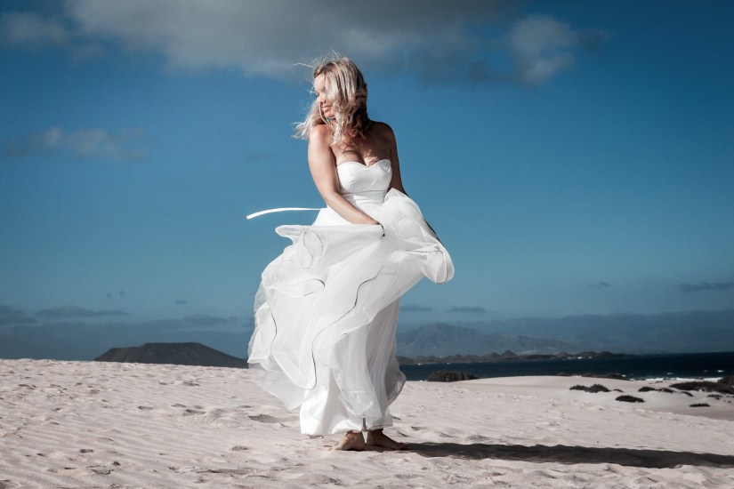 Affordable post-wedding photography - barefoot newlyweds play in Atlantic waves at Fuerteventura's most dramatic beach