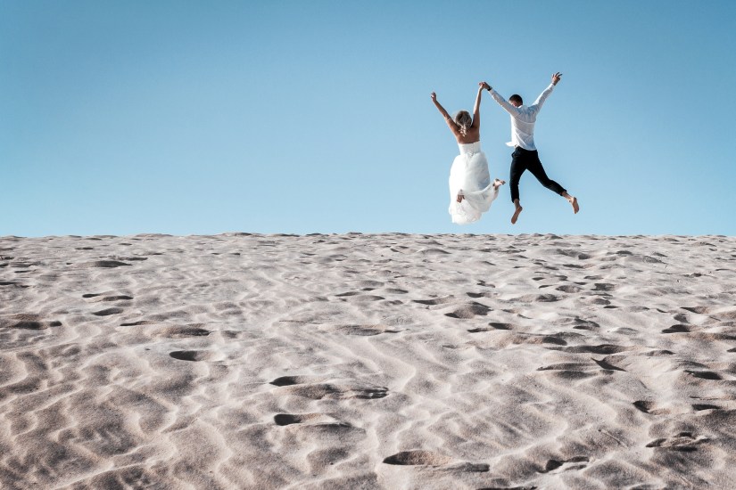Just married photo celebration - windblown couple portraits on Fuerteventura's wild coastline by professional photographer