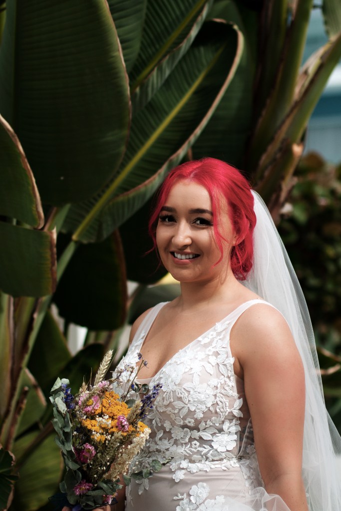 Best affordable photographer in Fuerteventura documents wedding procession - bridal party approaching flower-adorned arch with ocean backdrop