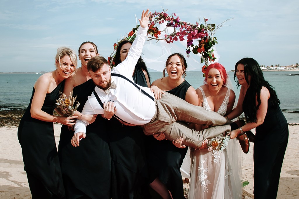 Top budget wedding photographer in Corralejo captures ceremony details - wooden arch flowers blowing in ocean breeze