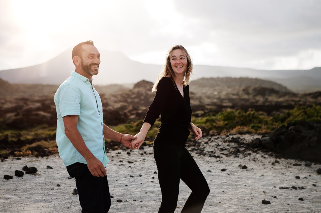 Fotografía impresionante de bodas en Lanzarote - pareja capturada caminando en un paisaje volcánico impresionante al atardecer. Confíe en un fotógrafo de bodas de primer nivel en Lanzarote Andrius Tekorius para capturar sus momentos especiales en el día de su boda