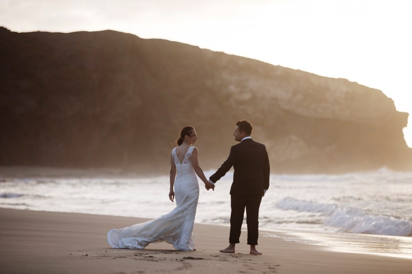 Elopement na czarnej plaży Fuerteventury - biała suknia i garnitur pięknie kontrastują z wulkanicznym piaskiem, uchwycone przez najlepszego fotografa ślubnego