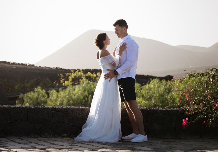 Intiem trouwreportage in La Geria: koppel zit op karakteristieke stenen muur in Lanzarote